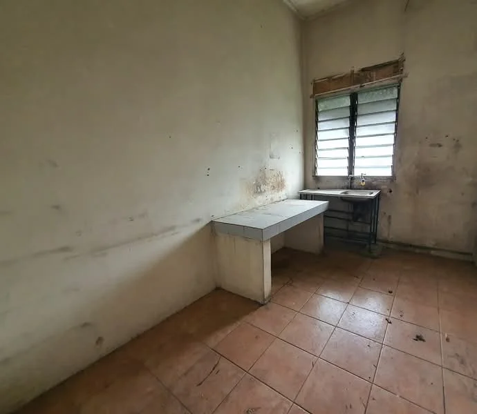 Room features: bare walls with peeling paint, tile flooring in beige, single window with louvered glass, concrete countertop, metal sink, exposed plumbing, no visible cabinetry, minimal natural light.