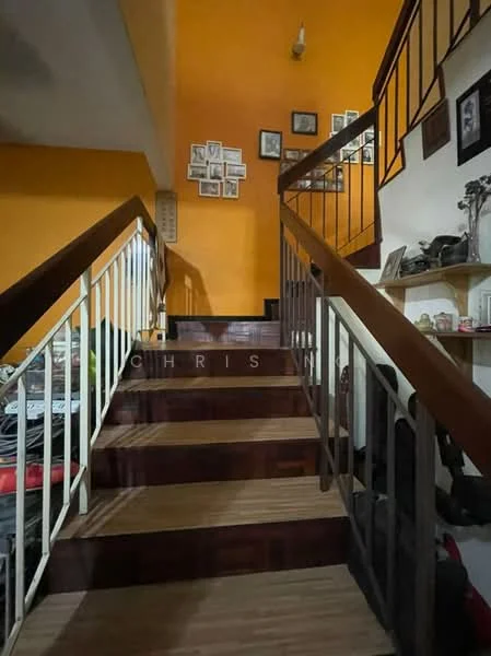 Room features: wooden staircase, metal railing, orange painted walls, framed photographs on wall, wooden shelves, laminate flooring, decorative items on shelves, light fixture on ceiling; style: traditional.