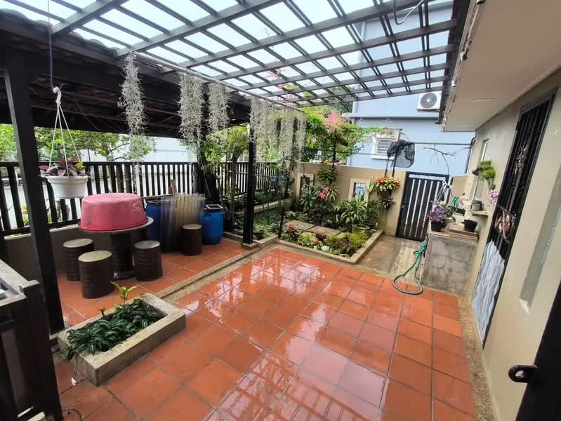 Room features: terracotta tile flooring, wooden pergola roof, greenery with potted plants, garden area with flower beds, decorative stone planter, outdoor water hose, black wooden fence, pink outdoor table, blue plastic barrel, seating area with cylindrical stools; style: contemporary; view: garden.