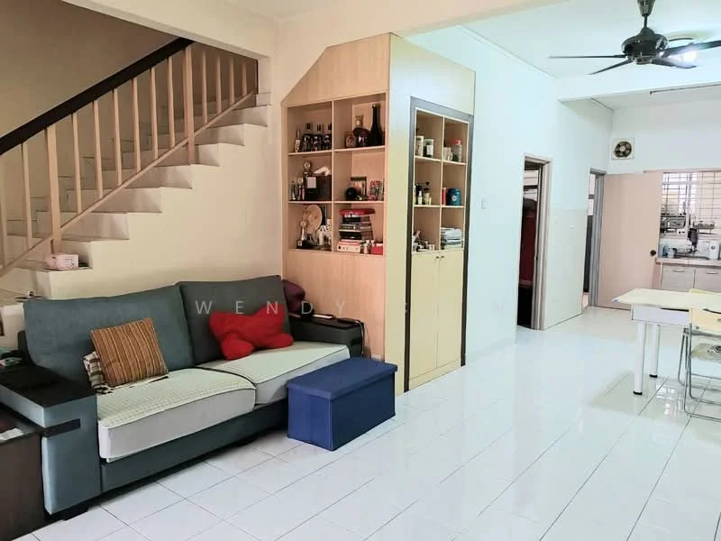 Living features: 3-seater fabric sofa in grey, red and brown decorative cushions, blue storage ottoman, built-in shelving unit with decorative items, white tiled flooring, ceiling fan, wall-mounted staircase, open layout to kitchen, natural light from window, neutral wall color; style: modern. Kitchen features: white cabinetry, stainless-steel sink, built-in kitchen appliances, open layout to living area, tile backsplash, window for natural light; style: modern.
