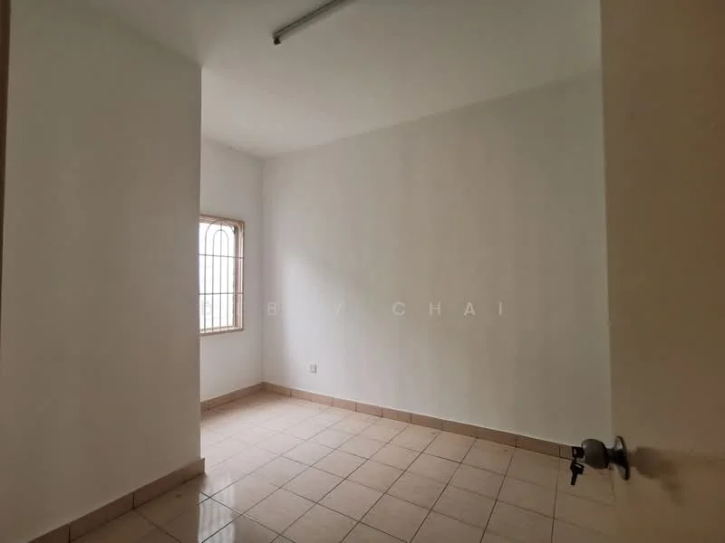 Room features: white painted walls, tile flooring, single window with metal grille, light fixture on ceiling, corner door, neutral color scheme.