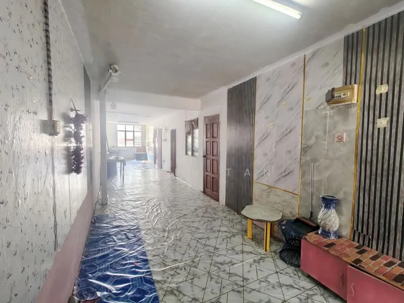 Room features: white painted walls with floral pattern, grey accent wall with vertical stripes, marble tile flooring, ceiling with fluorescent lighting, wooden door, decorative wall paneling, small round table, blue plastic covering on floor, wall-mounted electrical outlet, wall-mounted light fixture; style: modern.