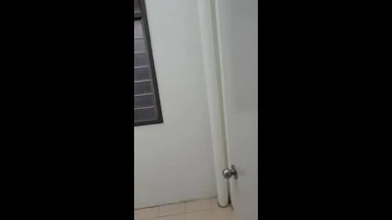 Room features: white painted walls, tile flooring, window with horizontal slats, door with knob handle.