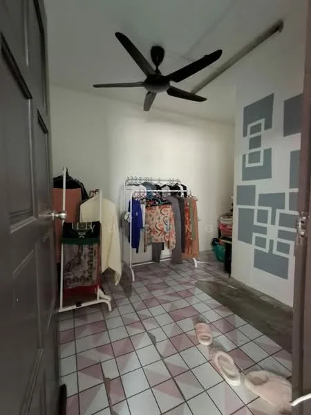 Room features: ceiling fan, wall with geometric pattern, white painted walls, pink and white tiled flooring, clothes rack, hanging clothes, door, light source.