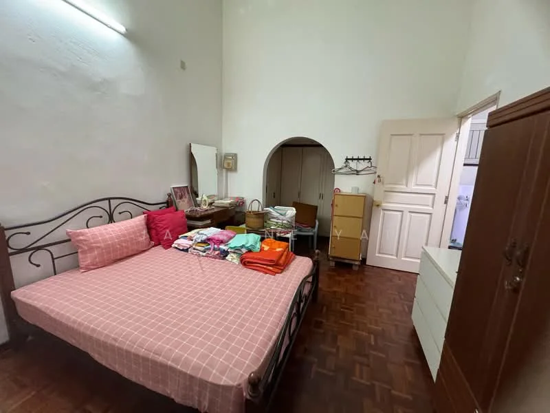 Bedroom features: queen-size bed with pink bedding, wooden flooring, white painted walls, built-in wardrobe, dressing table with mirror, arched doorway, decorative wall mirror, stacked boxes and folded clothes.