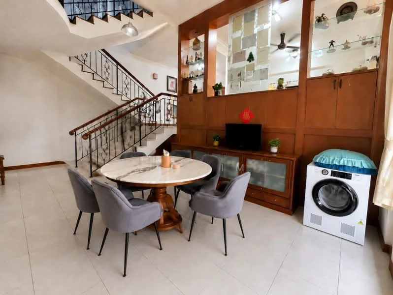 Dining features: round marble dining table, 6 upholstered dining chairs in grey, wooden base for dining table, built-in wooden cabinetry with glass display, wall-mounted TV, white washing machine, decorative plants on shelves, neutral tiled flooring, ceiling fan with light, staircase in background; style: modern.