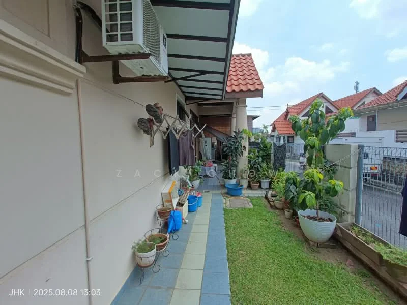 Exterior type: linked terrace house; features: red pitched tile roof, cream painted facade, manicured lawn, stone-paved walkway, potted plants, outdoor seating area, covered porch, air conditioning unit, fenced yard, surrounded by greenery; style: modern.