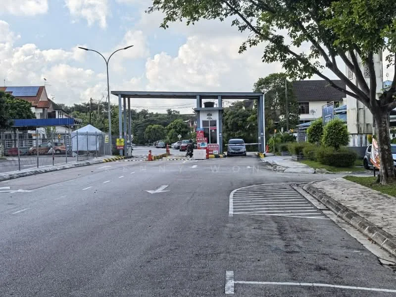 Exterior type: main entrance gate; features: guard house at entrance, boom gate, card-access turnstile, CCTV cameras visible, perimeter fence, gated entry, manicured landscaping, surrounded by mature greenery; style: modern.