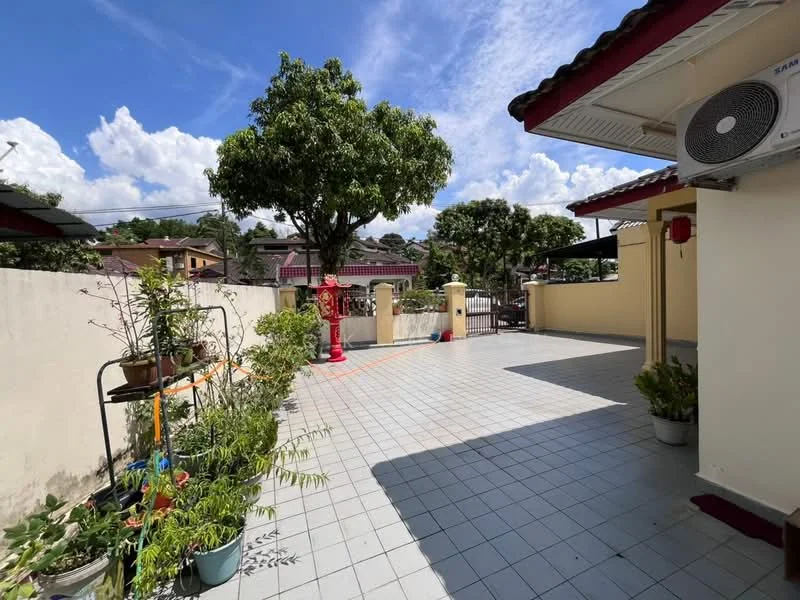 Exterior type: detached bungalow; features: paved outdoor area, manicured plants in pots, wall-mounted air conditioning unit, fenced perimeter, outdoor seating area, shade from trees, clear blue sky, sunny weather; style: modern.