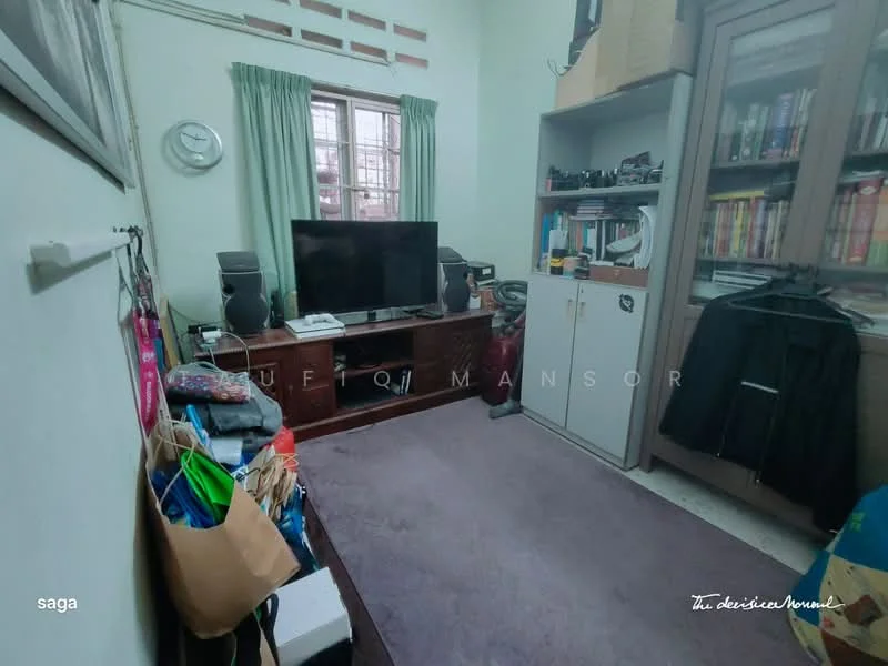 Room features: carpet flooring, light green painted walls, window with wooden frame, wall-mounted TV, wooden TV console, bookshelves, storage cabinet, cluttered with bags and items, clock on the wall, shelves with books and items.