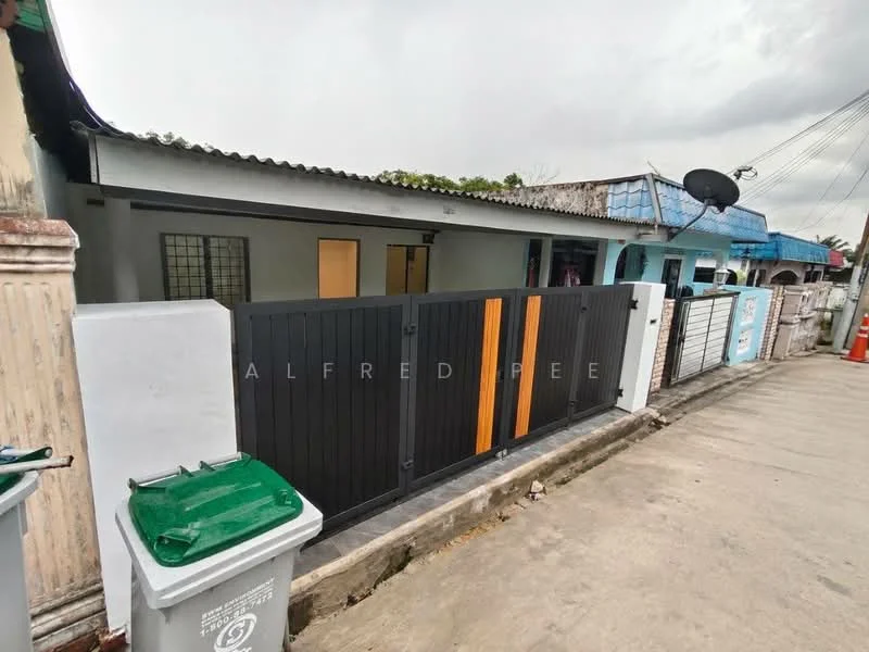 Exterior features: black and orange wooden gate, concrete fence, single-storey building, manicured lawn, paved driveway, satellite dish on roof, surrounding residential area, visible garbage bin; style: modern.