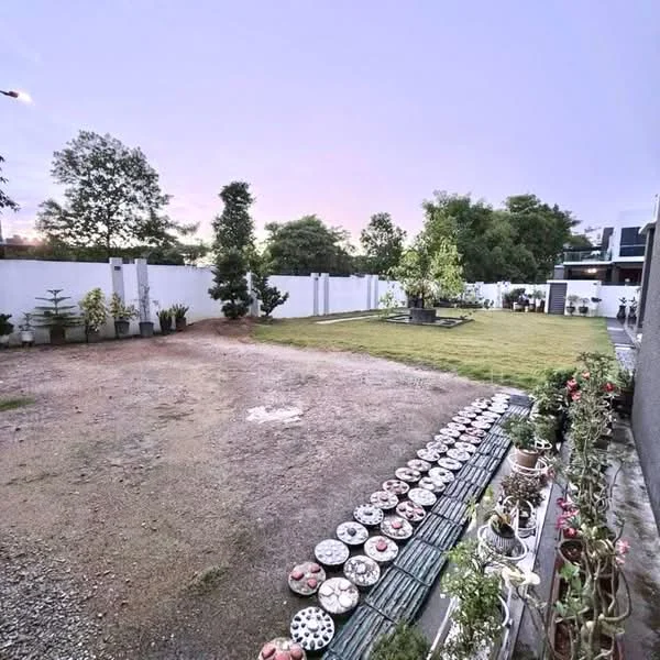 Exterior features: manicured lawn, gravel pathway, flower pots along the edge, white perimeter wall, mature trees, open space, landscaped garden; style: modern.