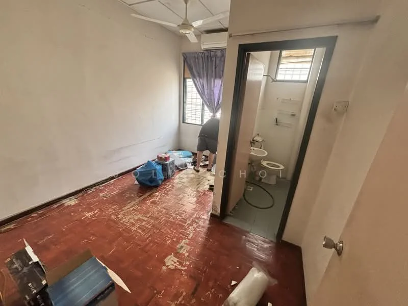 Room features: white painted walls, red tiled flooring, ceiling fan, window with sheer curtains, door leading to bathroom, visible plumbing fixtures, unfurnished, scattered items on floor.