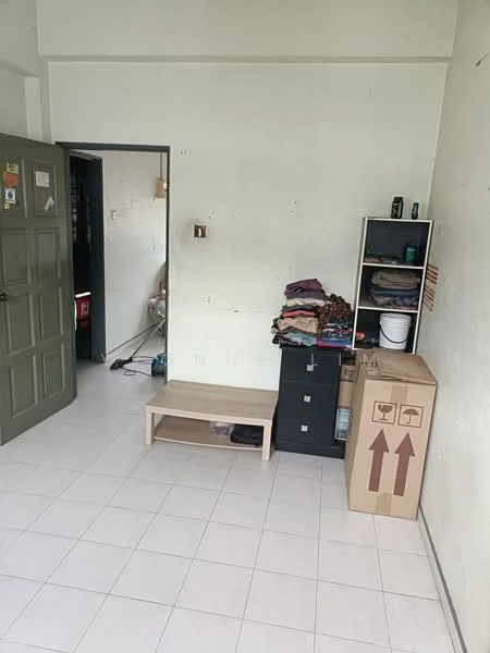 Room features: white painted walls, tile flooring, wooden bench, black storage cabinet, stack of folded blankets, cardboard box, door with green paint, open doorway leading to another room.