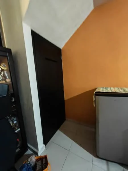 Room features: orange painted wall, grey painted wall, black door, tile flooring, corner space, refrigerator, decorative items on floor.