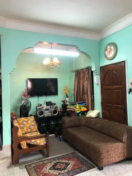 Living features: green painted walls, textured ceiling, chandelier with multiple bulbs, wall-mounted TV, wooden door, brown fabric sofa, orange patterned armchair, area rug with traditional pattern, decorative wall clock, curtains, stereo system, colorful toy storage, flooring with speckled tiles; style: traditional.