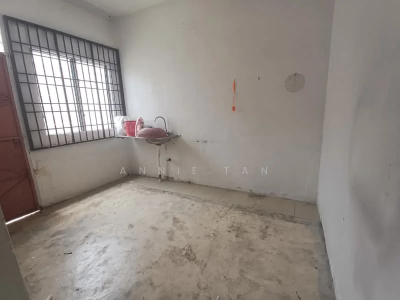 Room features: bare concrete flooring, white painted walls, single window with metal bars, red door, sink with no visible faucet, no visible lighting fixtures.