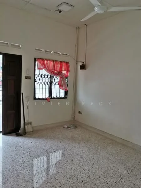 Room features: white painted walls, polished concrete flooring, ceiling fan, window with security grille, red sheer curtains, main entrance door, light fixture on ceiling, power outlet.