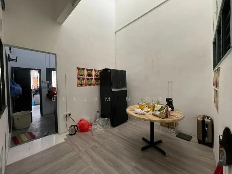 Room features: white painted walls, grey laminate flooring, round dining table, black refrigerator, kitchen appliances on table, plastic storage containers, wall-mounted shelves, window with metal grills, light fixture on ceiling.
