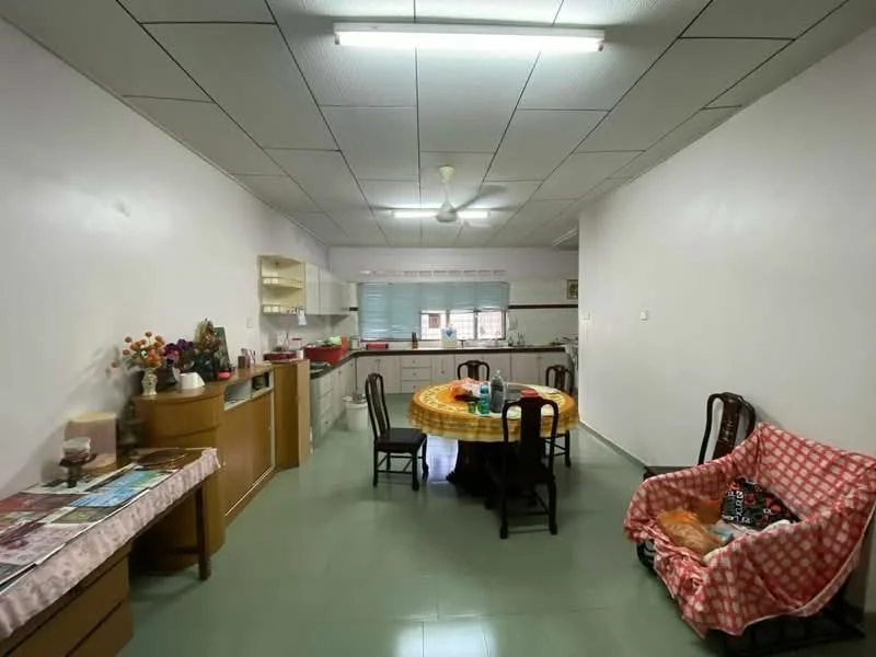 Room features: white painted walls, green vinyl flooring, dropped ceiling with fluorescent lights, ceiling fan, round dining table with yellow tablecloth, wooden dining chairs, sofa with red and white checkered cover, kitchen cabinetry, kitchen countertop, sink, kitchen appliances visible, decorative flowers on table, open space layout.