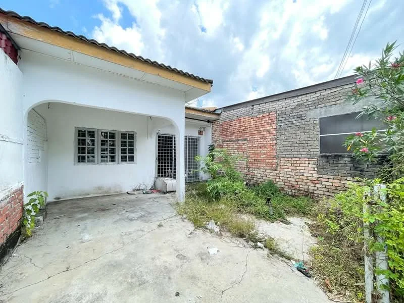 Exterior type: detached bungalow; features: exposed brick facade, white painted walls, flat roof, concrete flooring, overgrown garden area, gravel driveway, metal security grille, windows with metal grilles; style: traditional.