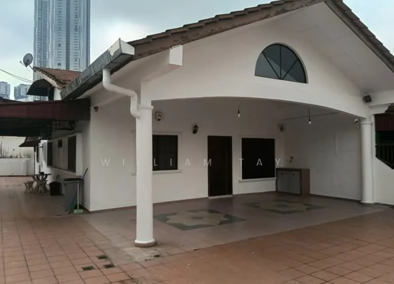 Exterior type: detached bungalow; features: white painted facade, pitched tile roof, open porch area, terracotta floor tiles, arched window, exterior wall lights, outdoor seating area, surrounded by greenery, visible high-rise buildings in background; style: modern.