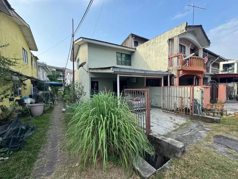 Exterior type: semi-detached house; features: two-storey structure, flat roof, cream painted facade, red brick accents, fenced yard, driveway with parking space, garden area with grass, surrounding greenery, adjacent properties visible, satellite dish on roof, outdoor staircase, balcony on upper floor; style: traditional.