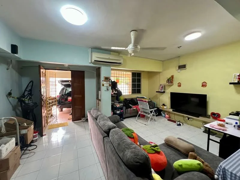 Living features: grey fabric sofa, colorful throw pillows, flat-screen TV on wall-mounted stand, white tiled flooring, ceiling fan, wall-mounted air conditioning unit, decorative wall shelf, large window with grid pattern, open doorway leading to another room, boxes for storage, foldable chair.
