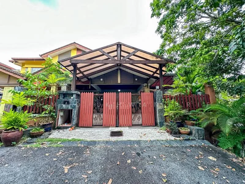 Exterior type: semi-detached house; features: red wooden gate, stone-paved driveway, tropical landscaping with ferns, manicured lawn, covered car porch, wooden beams in porch structure, decorative stone wall, green foliage surrounding the property; style: tropical-modern.