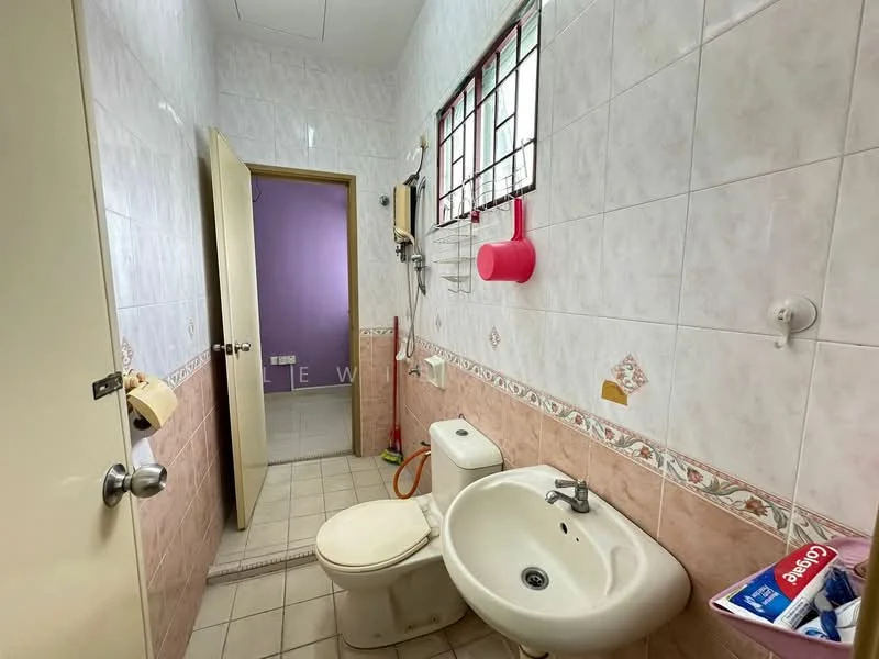 Bathroom features: white tiled walls, beige tiled flooring, one-piece toilet, pedestal sink, mirror above sink, window with metal grille, shower hose, toilet paper holder, wall-mounted soap dish, pink wall, towel rack.