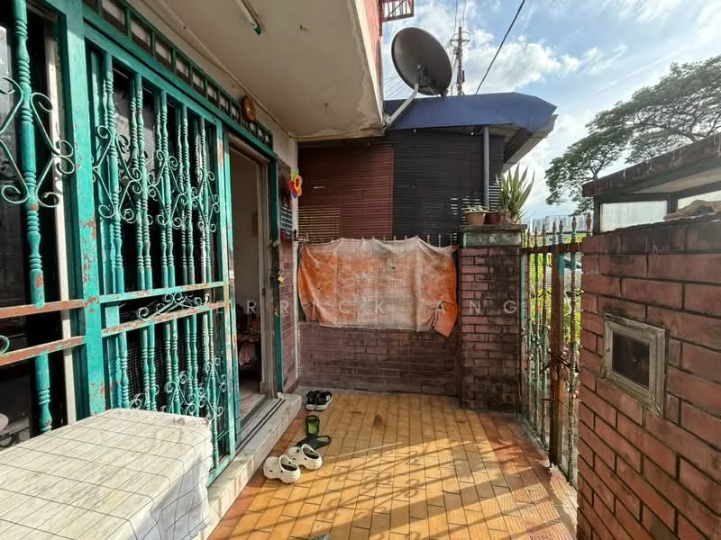 Exterior features: brick wall, green metal gate, tiled flooring, outdoor space, satellite dish, potted plants, shoes placed at entrance, partially covered area.