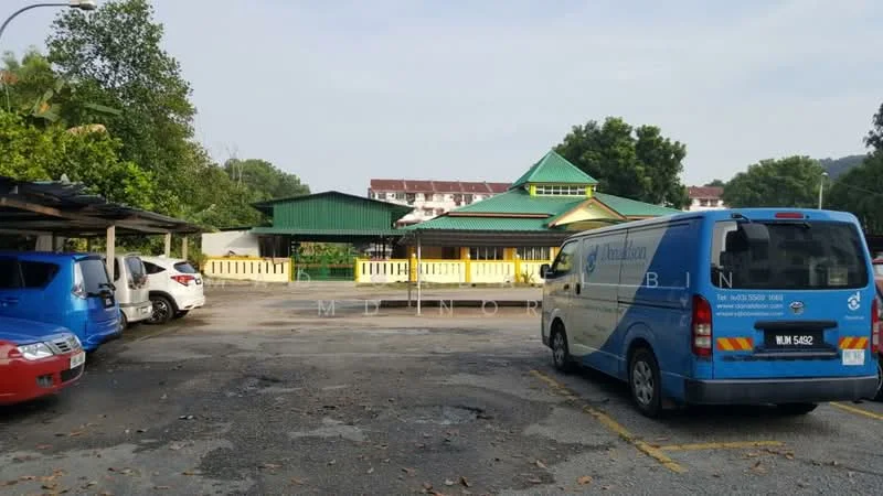 Exterior features: green painted facade, pitched roof, parking lot, multiple parked vehicles, surrounded by trees, open-air parking, yellow railings; style: traditional.