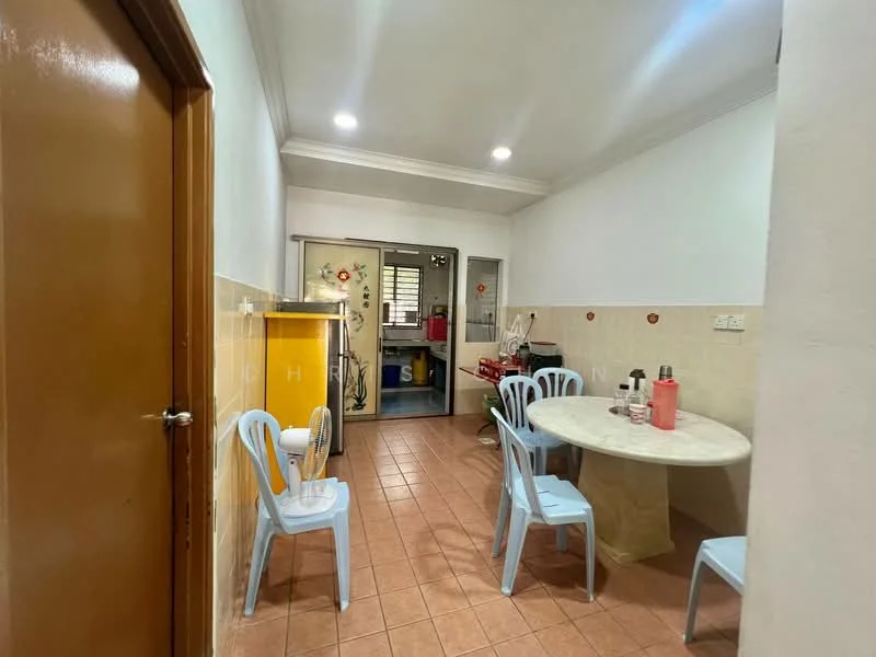 Kitchen features: white painted walls, cream tiled backsplash, brown tiled flooring, round dining table with marble top, 4 blue plastic chairs, kitchen cabinets, kitchen appliances visible, ceiling lights, wall-mounted fan.
