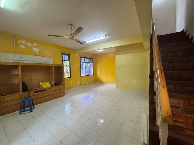 Living features: yellow painted walls, white tiled flooring, ceiling fan, large window with bars, wooden staircase, built-in wooden cabinet, blue plastic stool, fluorescent ceiling light.