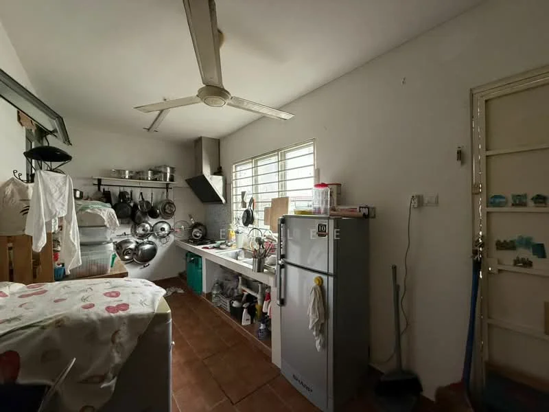 Kitchen features: white walls, tile flooring, ceiling fan, stainless-steel fridge, kitchen countertop, sink, wall-mounted cabinets, hanging pots and pans, window with horizontal slats, door leading to another room.