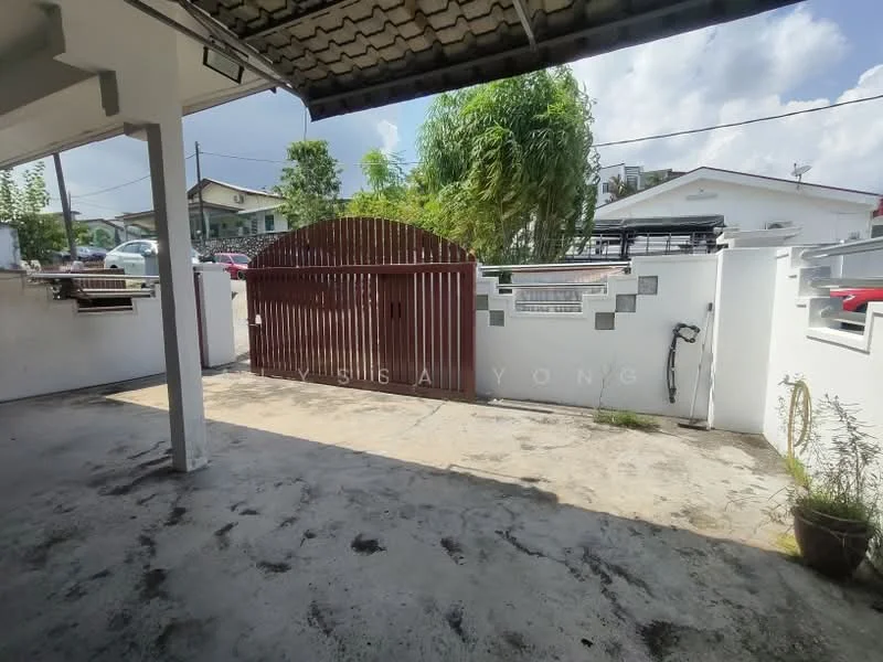 Exterior features: wooden gate, concrete walls, paved driveway, landscaped area with plants, roof overhang, sunlight casting shadows, surrounding residential buildings, open space; style: modern.