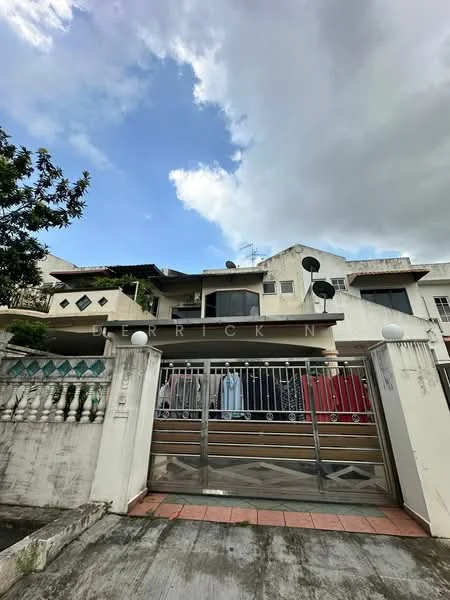Exterior type: linked terrace house; features: two-storey building, metal gate, brick facade, balconies on upper floor, satellite dishes on roof, decorative wall with diamond pattern, paved driveway, manicured shrubs, cloudy sky, urban setting; style: modern.