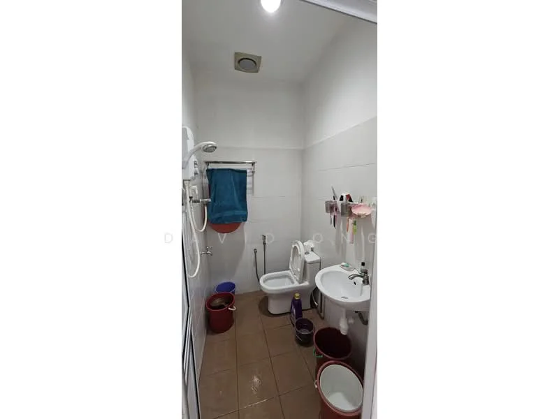 Bathroom features: white tiled walls, brown tiled flooring, one-piece toilet, sink with pedestal, chrome basin mixer faucet, showerhead, towel rack, mirror, hanging storage for toiletries, multiple colored buckets.