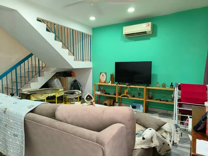Living features: light grey fabric sofa, wooden TV console, wall-mounted TV, green painted accent wall, white walls, ceiling fan, split air conditioning unit, grey tiled flooring, decorative items on shelves, laundry drying rack, staircase with blue railing; style: modern.
