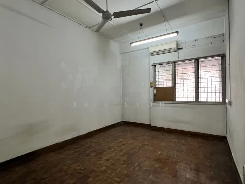 Room features: white painted walls, wooden flooring, ceiling fan, window with metal grille, air conditioning unit, light fixture, baseboard, no visible furniture.