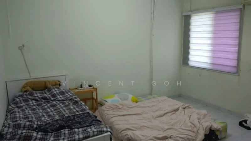 Bedroom features: two beds with bedding, plaid blanket, light-colored walls, white ceiling, window with sheer and colored blinds, tile flooring, wooden side table, unmade bedding.