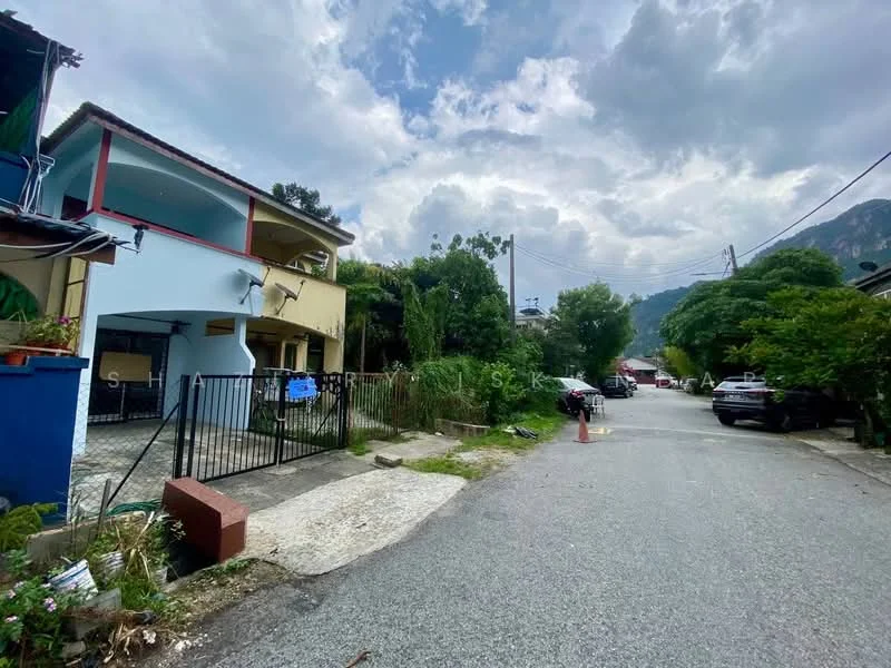 Exterior type: semi-detached house; features: blue painted facade, two-storey structure, gated entrance, manicured lawn, surrounded by greenery, driveway with interlocking pavers, adjacent to quiet residential street; style: modern.