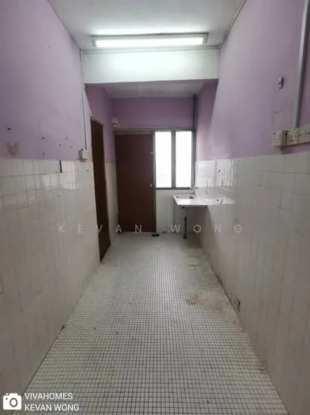 Room features: purple painted walls, white tiled flooring, window with natural light, door leading to another room, countertop along one wall, fluorescent ceiling light, tiles up to waist height, empty space.