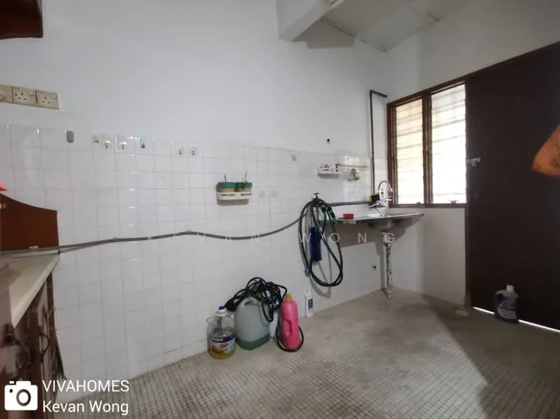 Room features: white tiled walls, grey tiled flooring, window with grid pattern, sink with faucet, wall-mounted cabinets, countertop, hose reel, cleaning supplies, door leading outside.