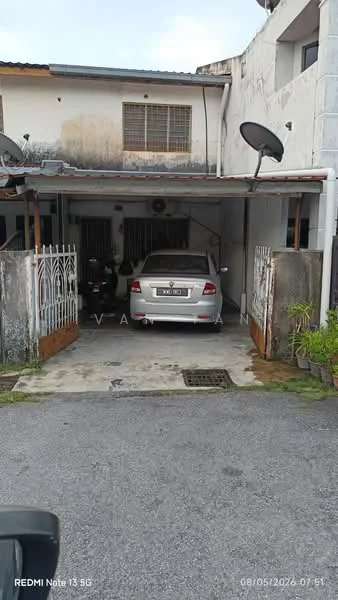 Exterior type: linked terrace house; features: car porch with awning, white painted facade, metal gate, two visible parked motorcycles, one parked car, concrete driveway, satellite dishes on roof, front garden area, gravel landscaping, exposed brick wall, single-storey, surrounded by residential buildings; style: traditional.