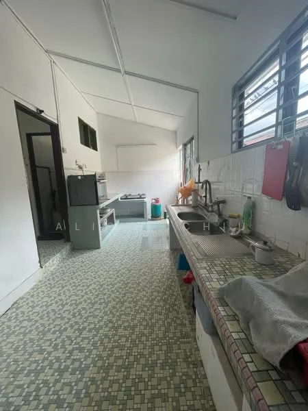 Kitchen features: white walls, grey tiled flooring, single-bowl stainless-steel sink, chrome pull-down faucet, countertop with mosaic tile, built-in cabinets, freestanding stove, refrigerator, window with metal grilles, wall-mounted shelves, kitchen utensils visible.