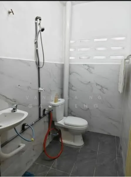 Bathroom features: white ceramic toilet, chrome basin mixer faucet, small sink with pedestal, shower with handheld shower head, grey marble tile cladding on walls, grey floor tile, exposed plumbing, window with decorative ventilation blocks; style: modern.