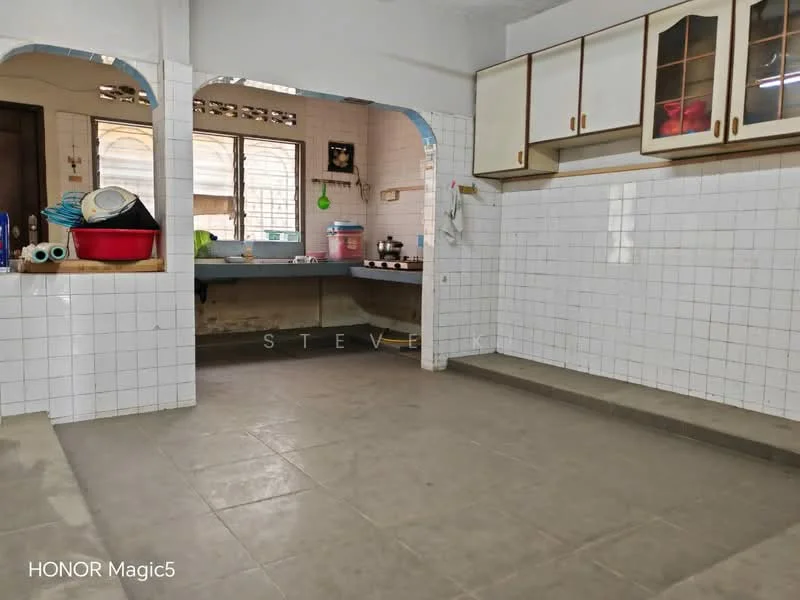 Kitchen features: white tiled walls, grey tiled flooring, L-shaped countertop, sink, wooden cabinetry with glass fronts, window above countertop, open shelving, kitchen utensils visible, cooking appliances visible.