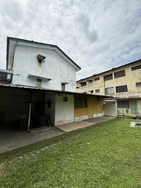 Exterior type: semi-detached house; features: two-storey building, white painted facade, yellow accent wall, flat roof, manicured lawn, concrete patio area, windows with grilles, outdoor space, adjacent building with multiple windows; style: traditional.