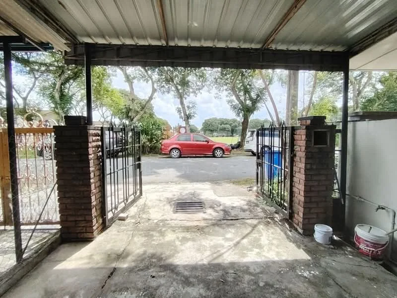 Exterior features: brick gate pillars, metal gate, concrete driveway, paved walkway, surrounding greenery, view of street, visible parked car, open space, metal roof.